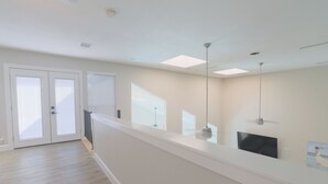 Un hall d’hôtel moderne avec un long comptoir d’accueil, un téléviseur à écran plat et un ventilateur de plafond.