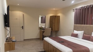 A hotel room with a bed, a desk, a chair, a TV, and a wardrobe. - Sukoon Prestige Palace (Bhopal)