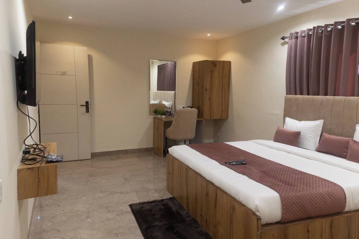 Una camera d'albergo con un letto, una scrivania, una sedia, una televisione e un armadio.