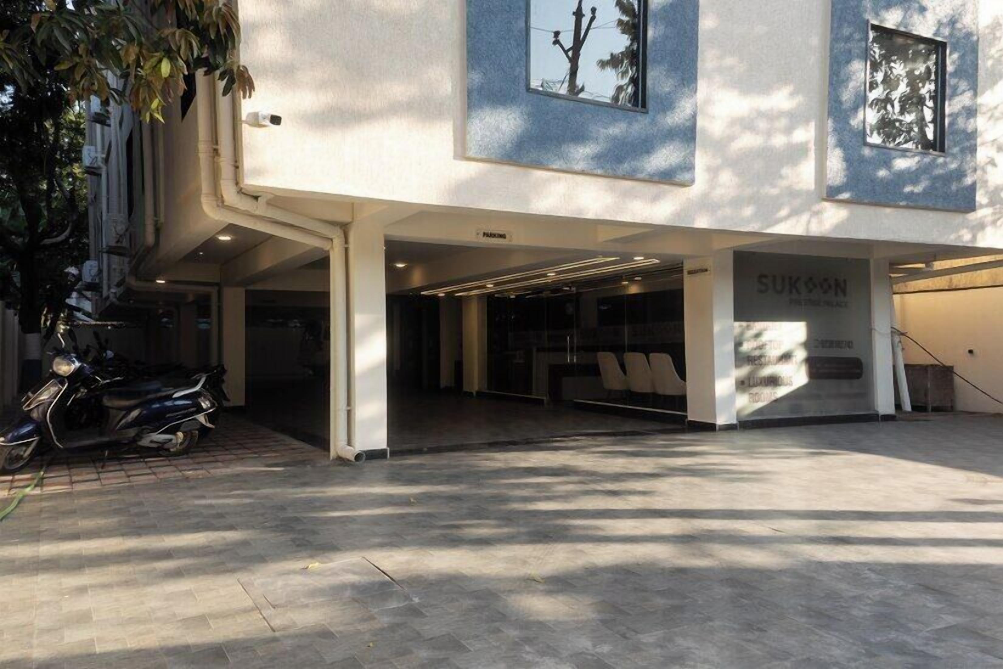A modern building with a covered entrance, a motorcycle parked outside, and a sign for 'SUKOSON'.