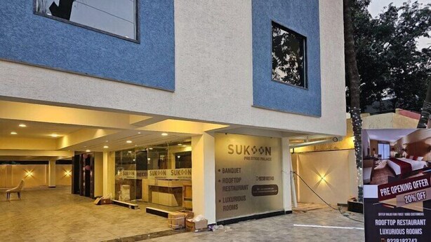 A hotel exterior with a signboard advertising a rooftop restaurant and luxurious rooms. - Sukoon Prestige Palace (Bhopal)