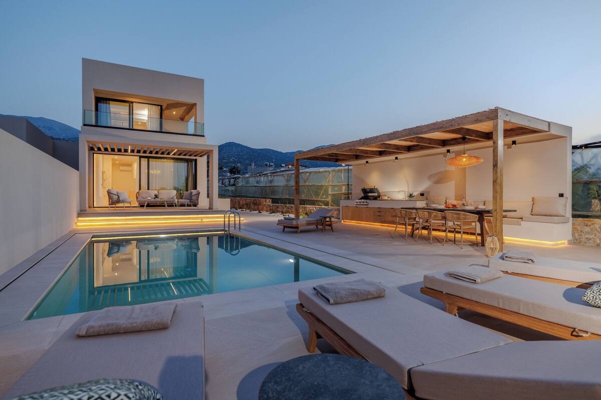 A modern outdoor pool area with lounge chairs, a dining area, and a covered seating area.