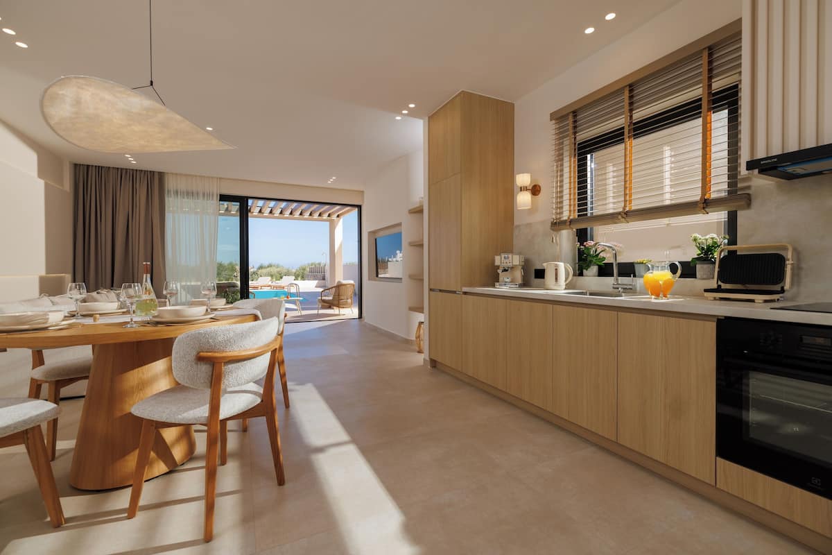 A modern kitchen with a dining area, wooden cabinets, and a view to the outside.