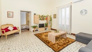 Un salon comprenant un canapé, une table basse, un meuble pour la télévision et un tapis décoratif.