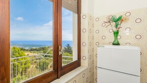 Une pièce avec une fenêtre donnant sur un paysage, un appareil électroménager blanc et des carreaux muraux à motifs.