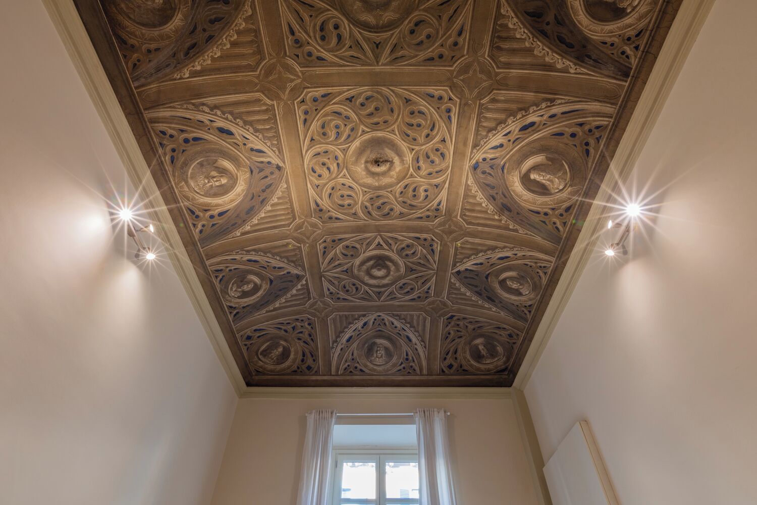 A room with a decorative ceiling featuring intricate patterns and recessed lighting.