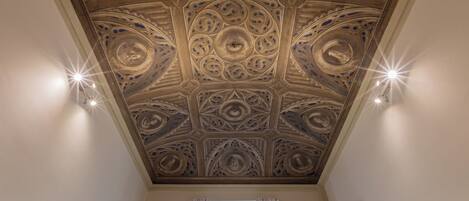 A room with a decorative ceiling featuring intricate patterns and recessed lighting.