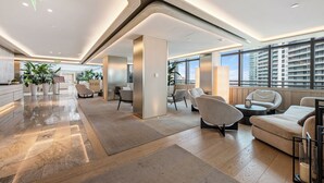 Un vestíbulo espacioso con diseño moderno, que incluye un mostrador de recepción, zona de estar y amplias ventanas con vistas a la ciudad.