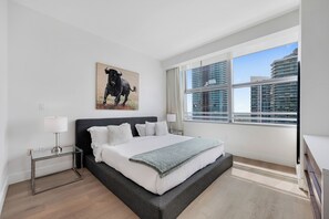 Ein modernes Schlafzimmer mit einem großen Bett, Blick auf die Stadt und einem Bullenbild an der Wand.