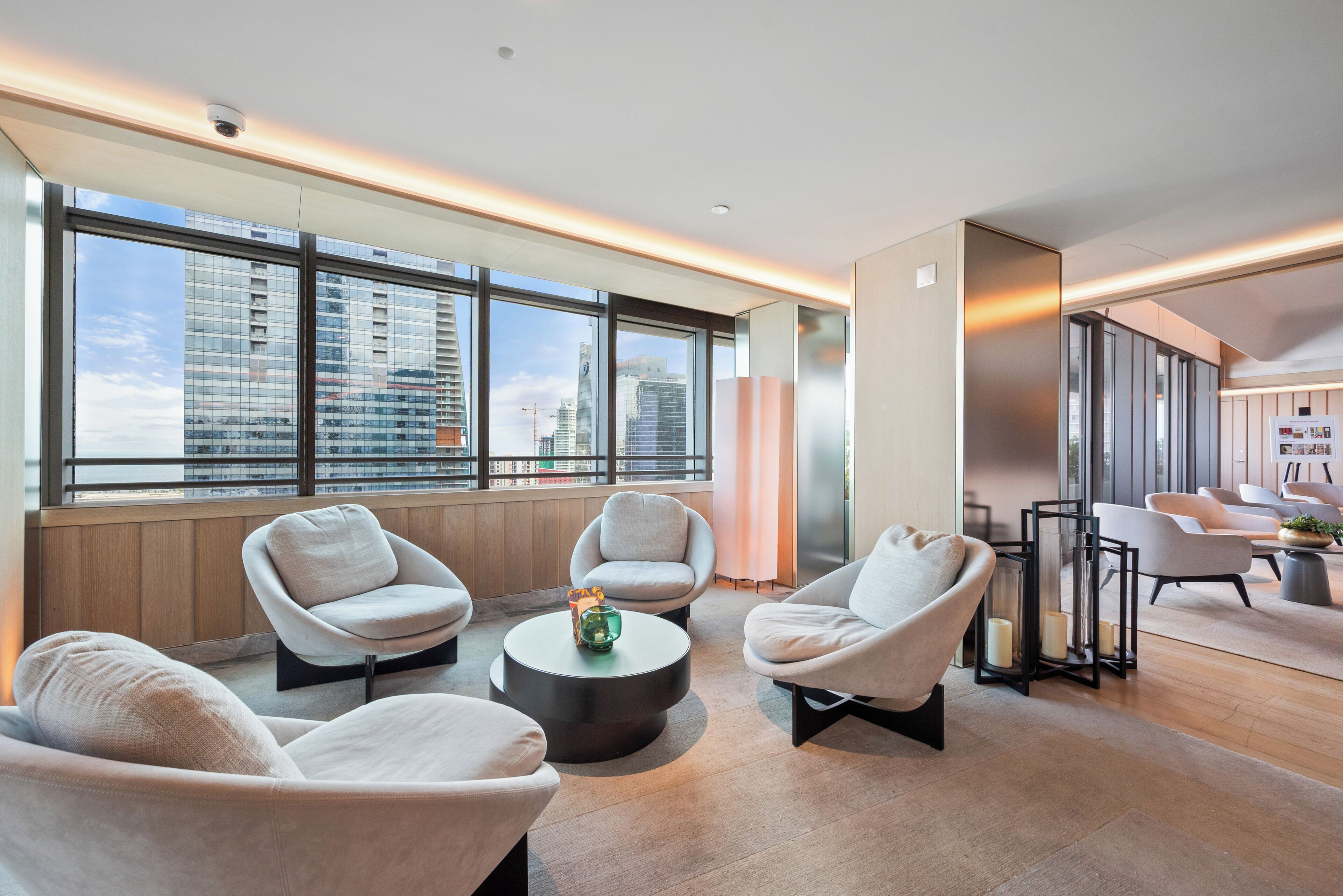 A modern lounge area with comfortable seating, large windows, and a view of the cityscape.
