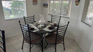 A dining area with a round table set for four, surrounded by four chairs.
