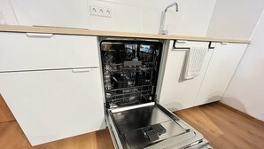 A kitchen with a built-in dishwasher, wooden flooring, and white cabinetry. - Friendly warm apartment between Alb and Rems incl. sauna (Böbingen)
