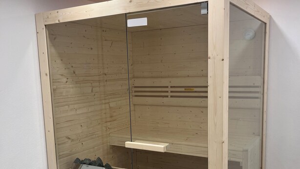 A wooden sauna with glass doors, a bench, and a small wooden table. - Friendly warm apartment between Alb and Rems incl. sauna (Böbingen)