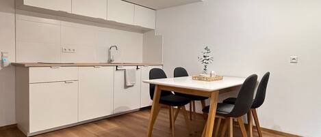 Una cocina moderna con armarios blancos, una mesa de comedor de madera y sillas negras.