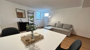 A modern living room with a white table, black chairs, a beige sofa, and a small plant on the table. - Friendly warm apartment between Alb and Rems incl. sauna (Böbingen)