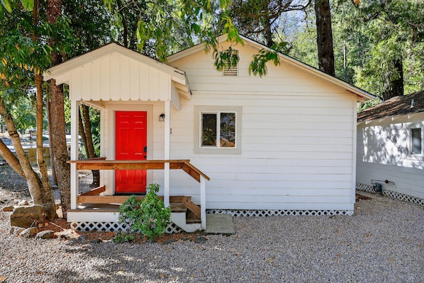 A small, single-story building with a red door and a small porch.