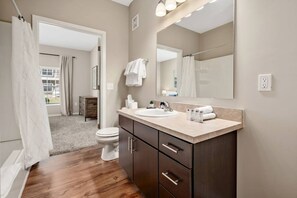 A modern bathroom with a wooden floor, a sink, a mirror, and a toilet. - Pet-friendly 2BR On 1st Floor Parking W D (Westerville)
