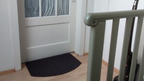 A staircase leading to a room with a door that has a window with curtains. - Apartment 'Ferienwohnung Für Max 2 Personen' (Hannover)