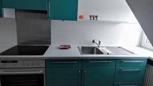 A kitchen with teal cabinets, a stainless steel sink, and a built-in oven. - Apartment 'Ferienwohnung Für Max 2 Personen' (Hannover)