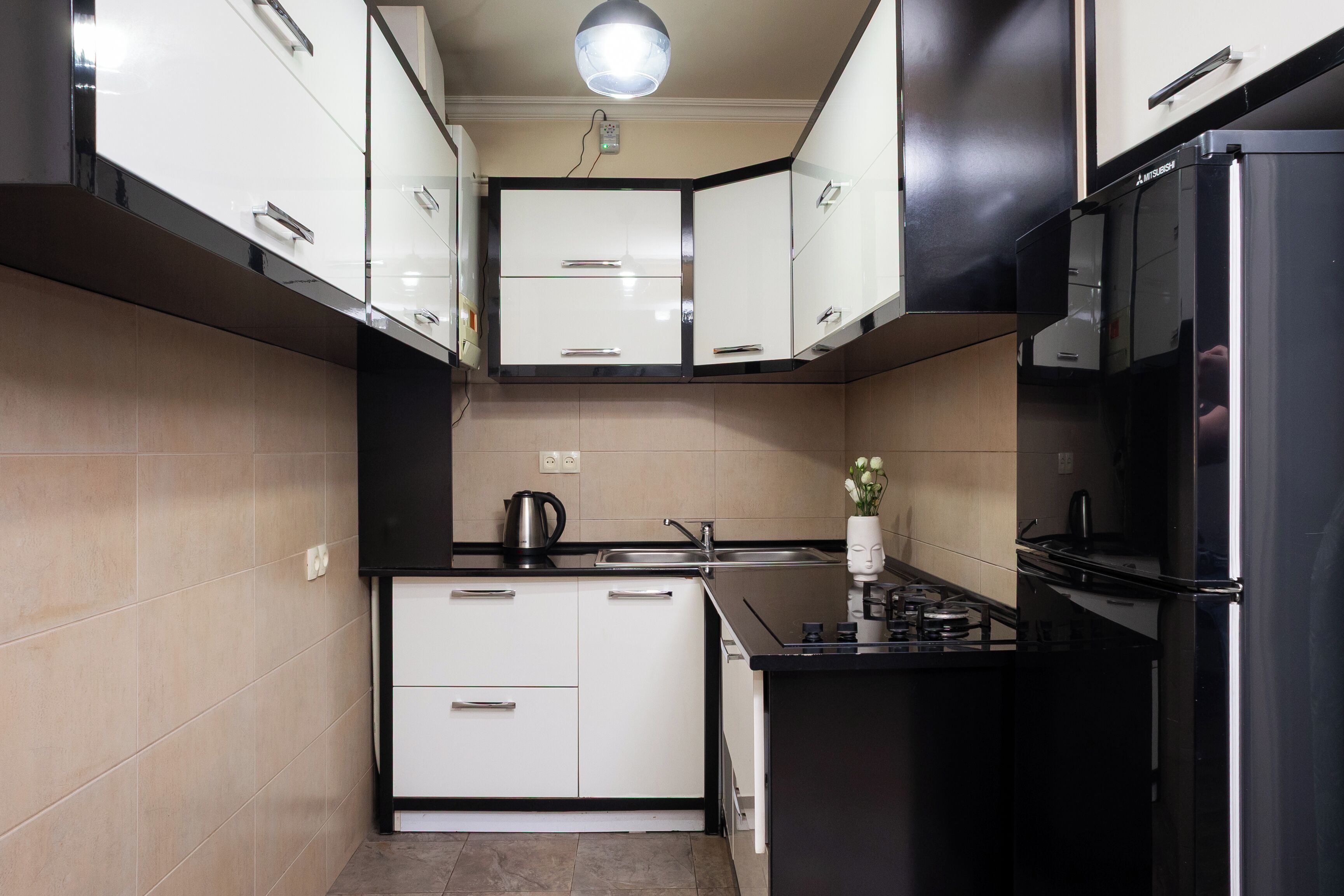 A modern kitchen with white cabinets, a black refrigerator, and a gas stove.