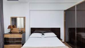 A bedroom with a bed, a dresser, a mirror, and a wardrobe.