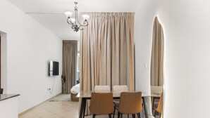 A modern dining area with a glass table, two brown chairs, and a chandelier. - Diamond 6 Residences by CEG Group (Dubai)