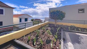 A residential area with a paved walkway, a tree, and buildings with white and yellow walls.