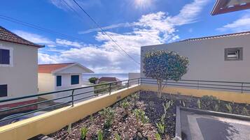 A residential area with a paved walkway, a tree, and buildings with white and yellow walls.