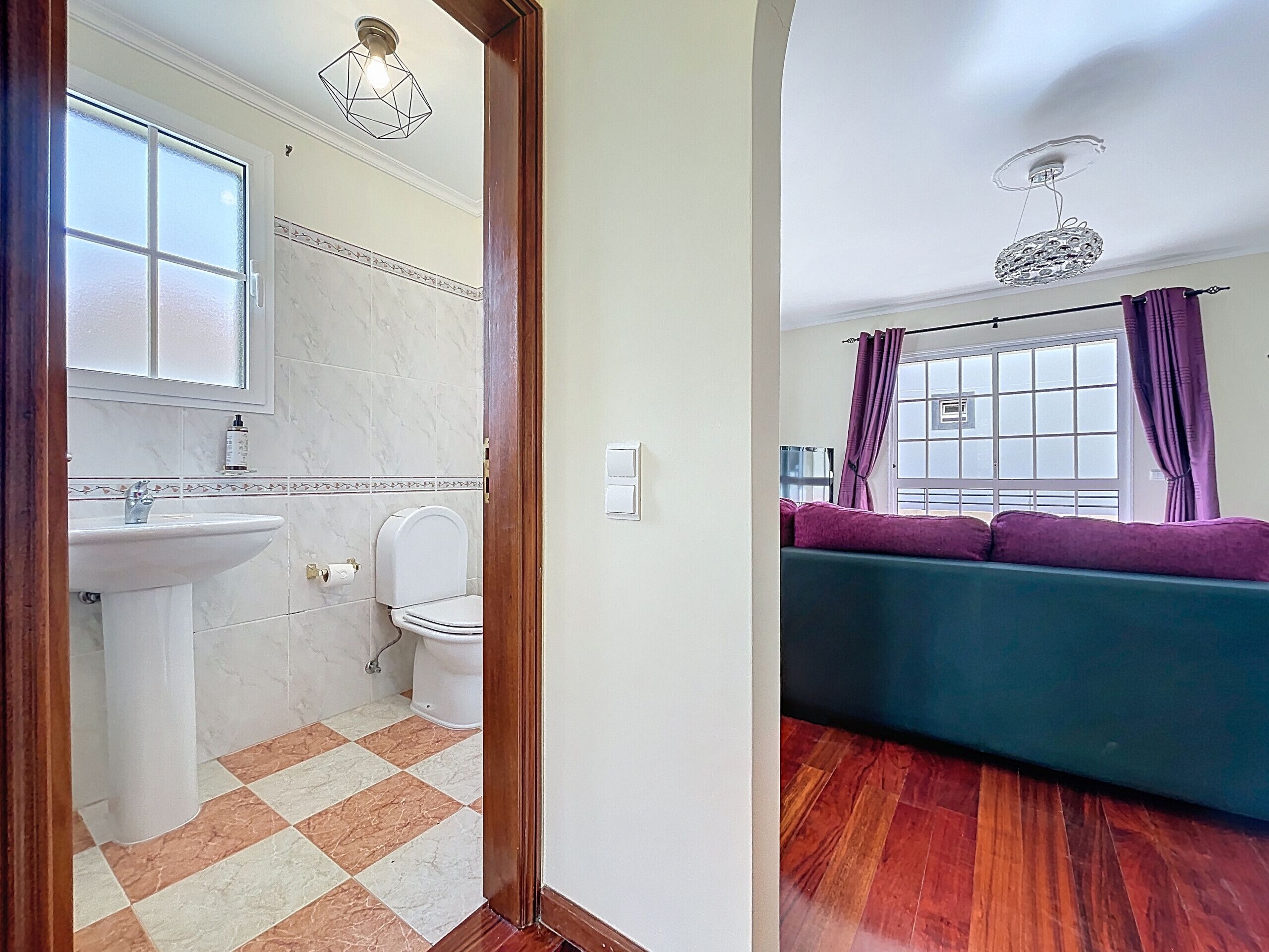 Ein Badezimmer mit Waschbecken, Toilette und einem Fenster mit Vorhängen.