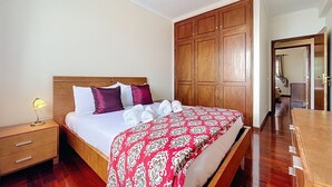 A hotel room with a wooden bed, a nightstand, a wardrobe, and a mirror.