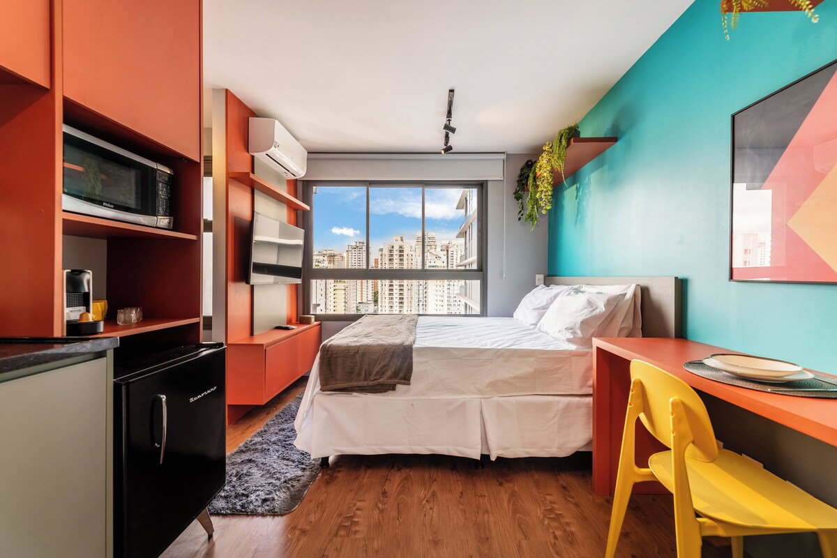 Una camera da letto moderna con un letto, una scrivania e un angolo cottura.