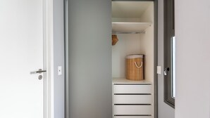 Ein begehbarer Kleiderschrank mit Schiebetüren, ein Holzkorb und mehrere Schubladen.