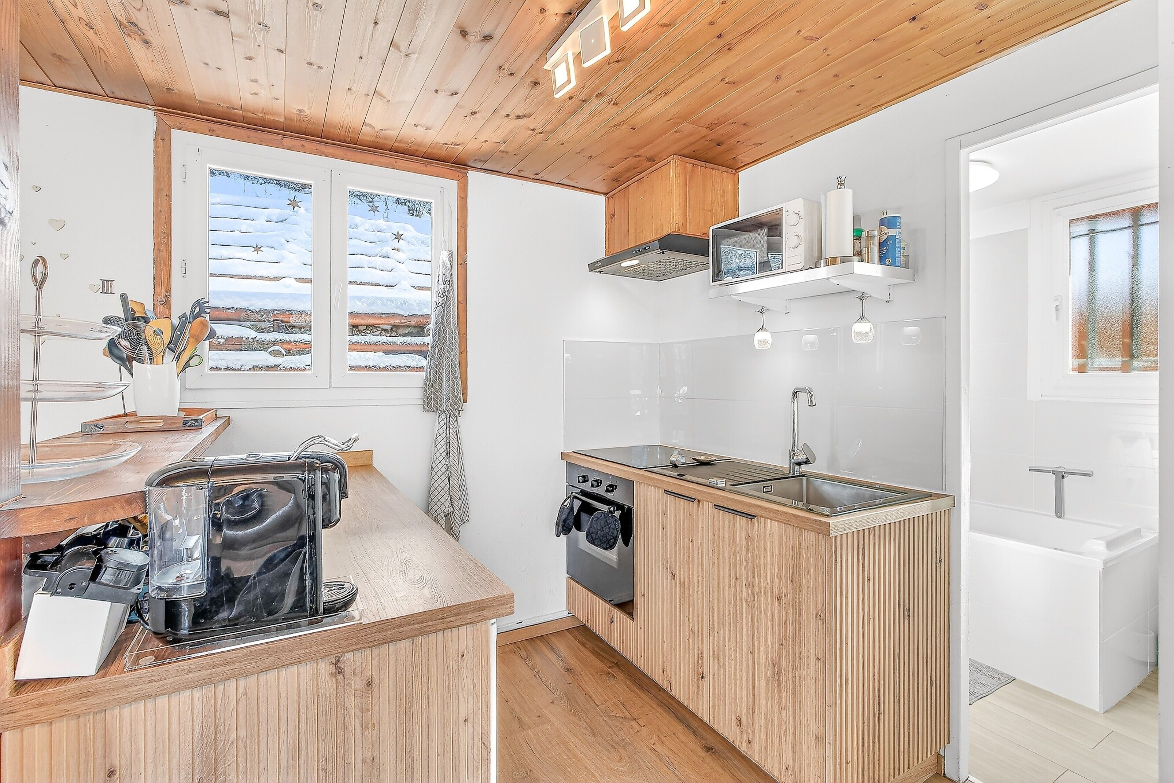 Une cuisine moderne avec des meubles en bois, un four encastré, un four à micro-ondes et un évier.