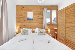 Un lit double avec une literie blanche, des murs recouverts de panneaux de bois, un tableau et deux lampes de chevet.