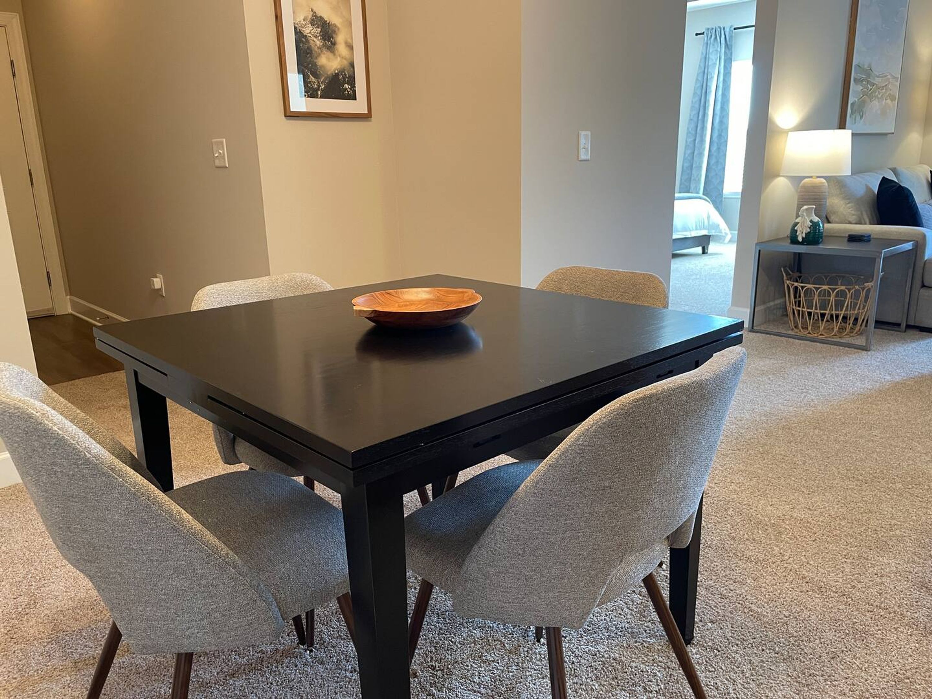 A dining area with a dark wooden table and four grey upholstered chairs.