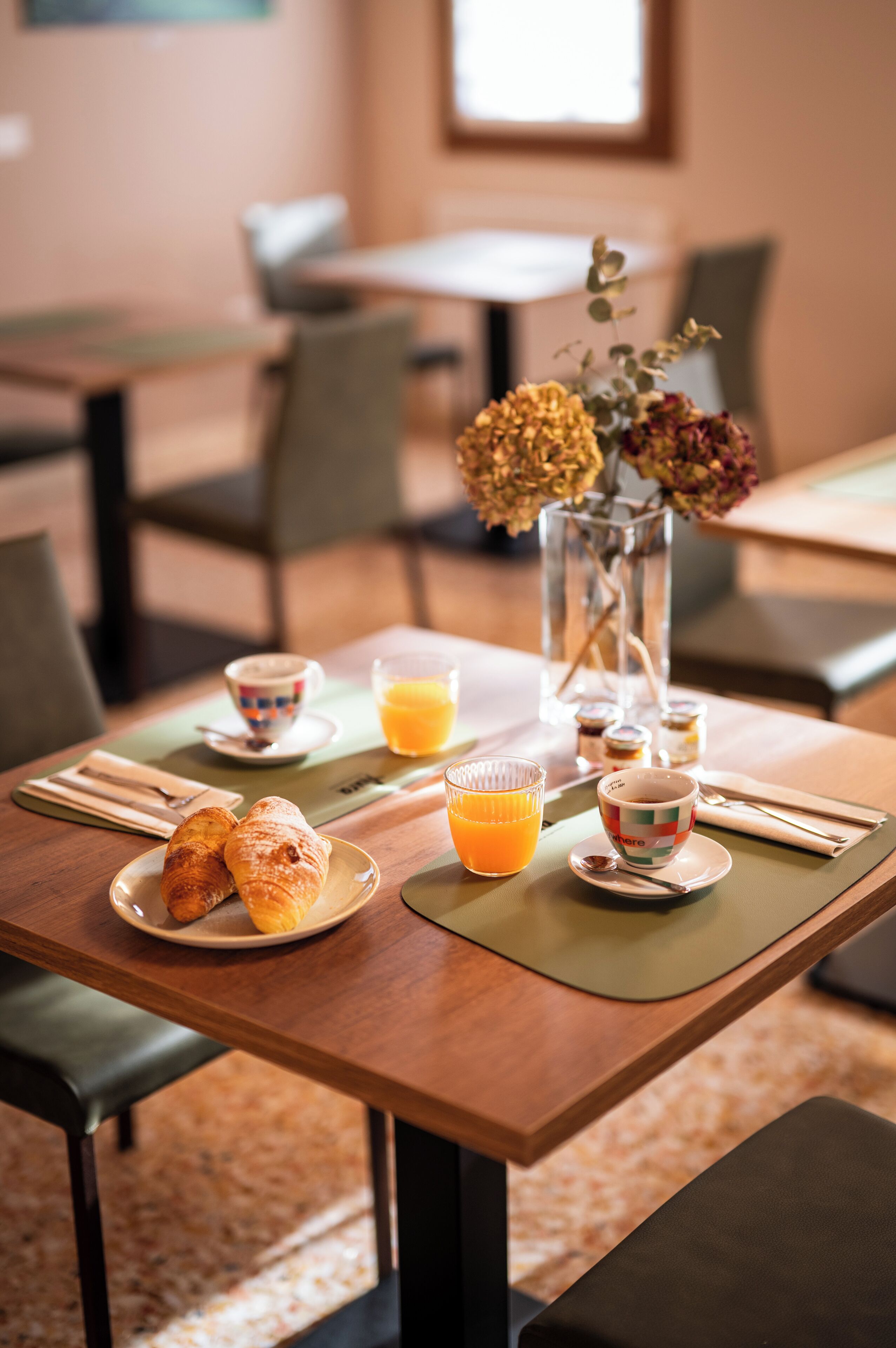 Ein Frühstückstisch mit Croissants, einer Tasse Kaffee und einem Glas Orangensaft.