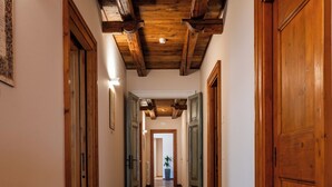 Un pasillo con pisos de madera y puertas que conduce a una habitación con vista a una planta.