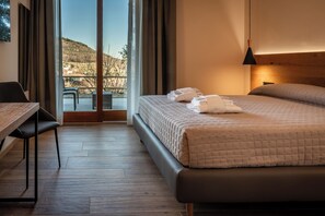 A hotel room with a bed, a desk, and a view of a hillside. - Aura - Dimore ad Arquà Petrarca (Arquà Petrarca)
