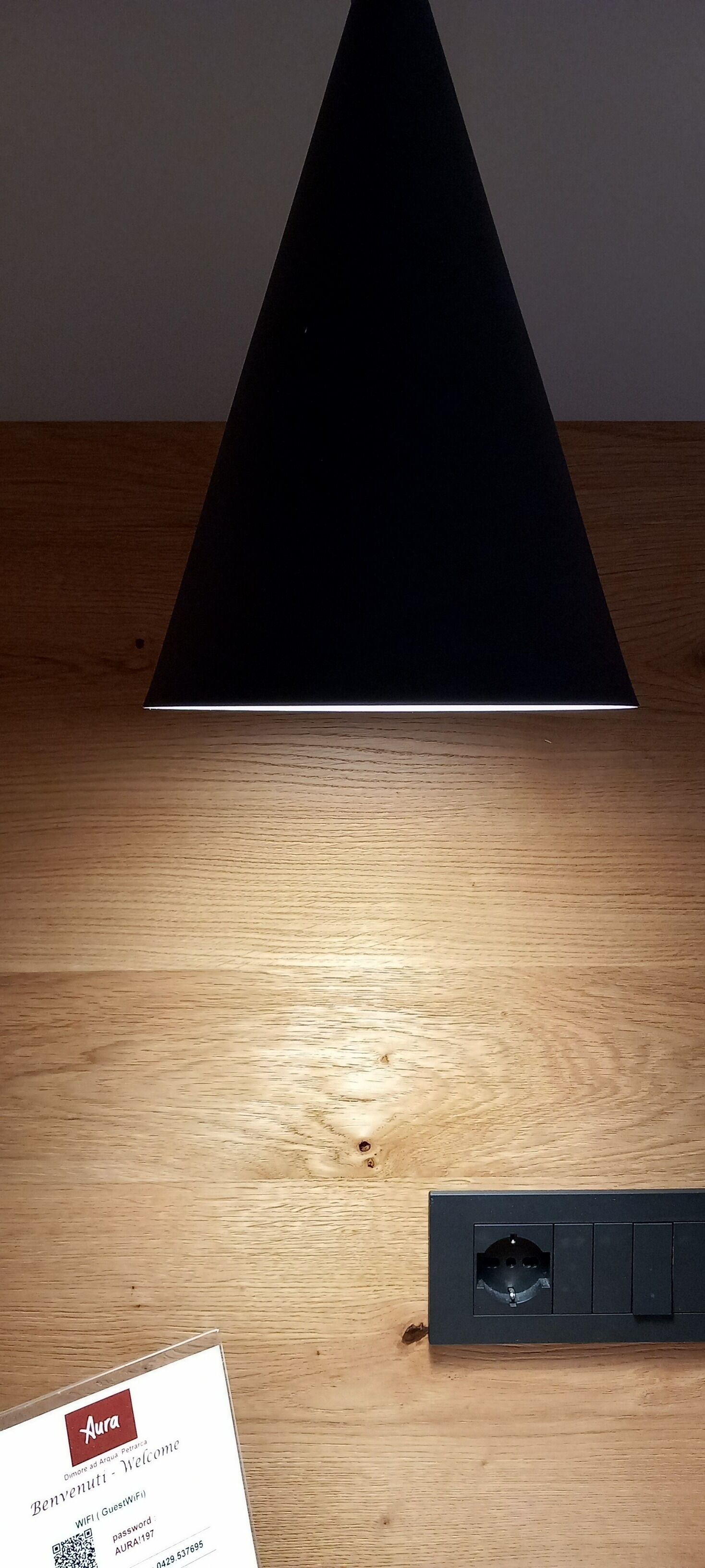 A black triangular object on a wooden surface with a sign containing a QR code and text.