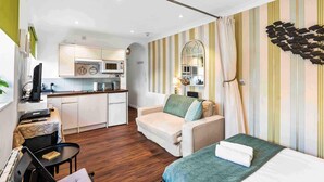 A compact hotel room with a kitchenette, a sofa, a bed, and a small table. - Starfish Studio By My Getaways (Brighton)