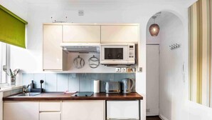 A modern kitchen with white cabinets, a microwave, a toaster, and a coffee maker. - Starfish Studio By My Getaways (Brighton)