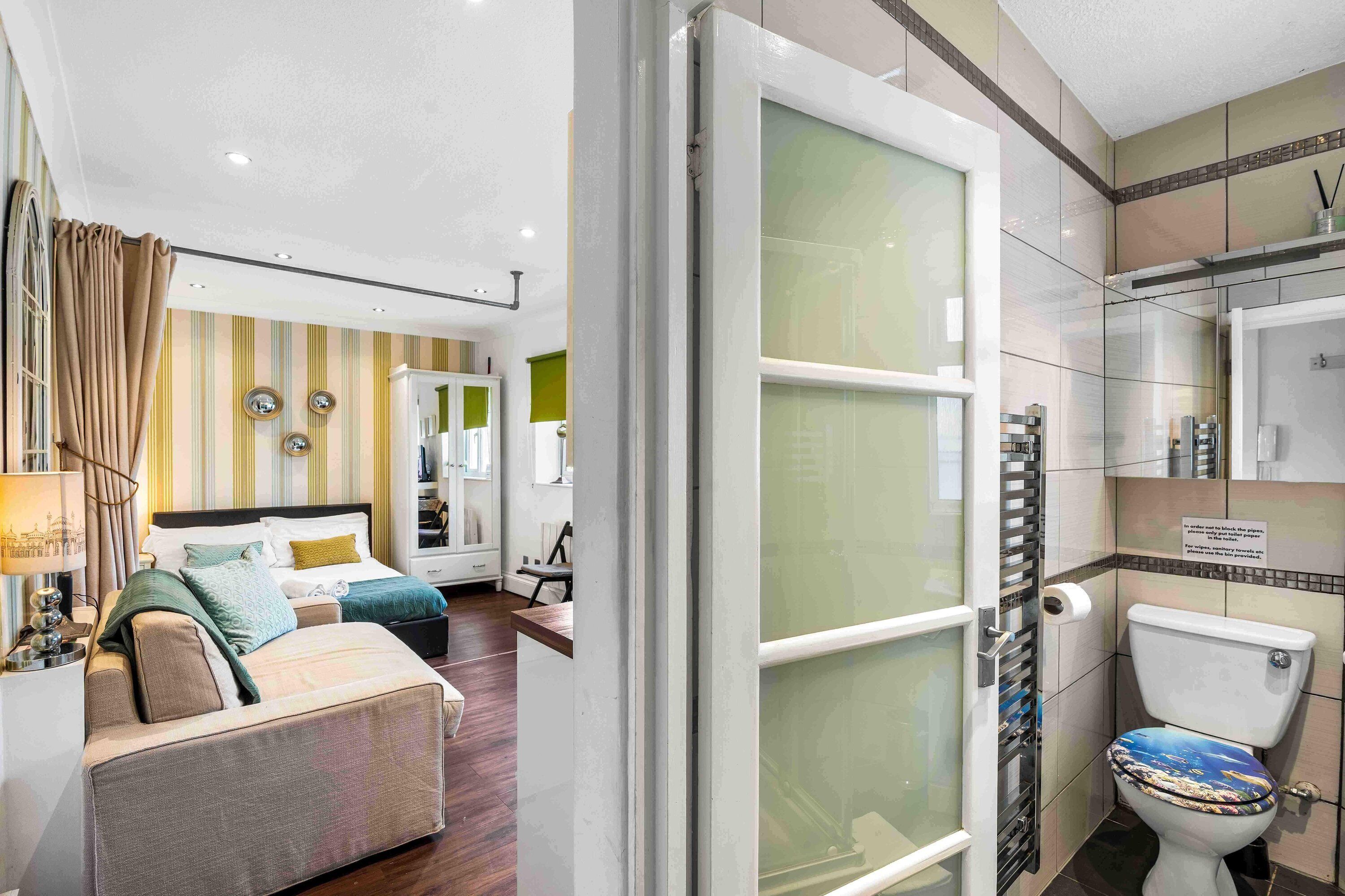 Une chambre d’hôtel comprenant un lit, un canapé, un bureau et une salle de bain avec des toilettes et un lavabo.