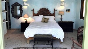 A bedroom with a large bed, two bedside tables with lamps, a ceiling fan, and a decorative mirror. - Mi Media Naranja-Ocean view luxury casita (San Pancho)