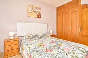 A bedroom with a bed, wooden wardrobe, and a nightstand with lamps. - Apartment 'Penthouse with Private Pool' with Mountain View, Wi-Fi and Air Conditioning (Nerja)