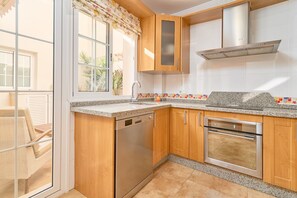 A kitchen with wooden cabinets, a stainless steel dishwasher, and an oven. - Apartment 'Penthouse with Private Pool' with Mountain View, Wi-Fi and Air Conditioning (Nerja)