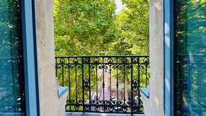A balcony with a wrought iron railing, a view of a tree-lined street, and a clear sky. - T2 "Mediterranean" apartment in the center of Narbonne (Narbonne)
