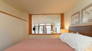 Une chambre avec un grand lit, une fenêtre avec des rideaux et des œuvres d’art encadrées accrochées au mur.