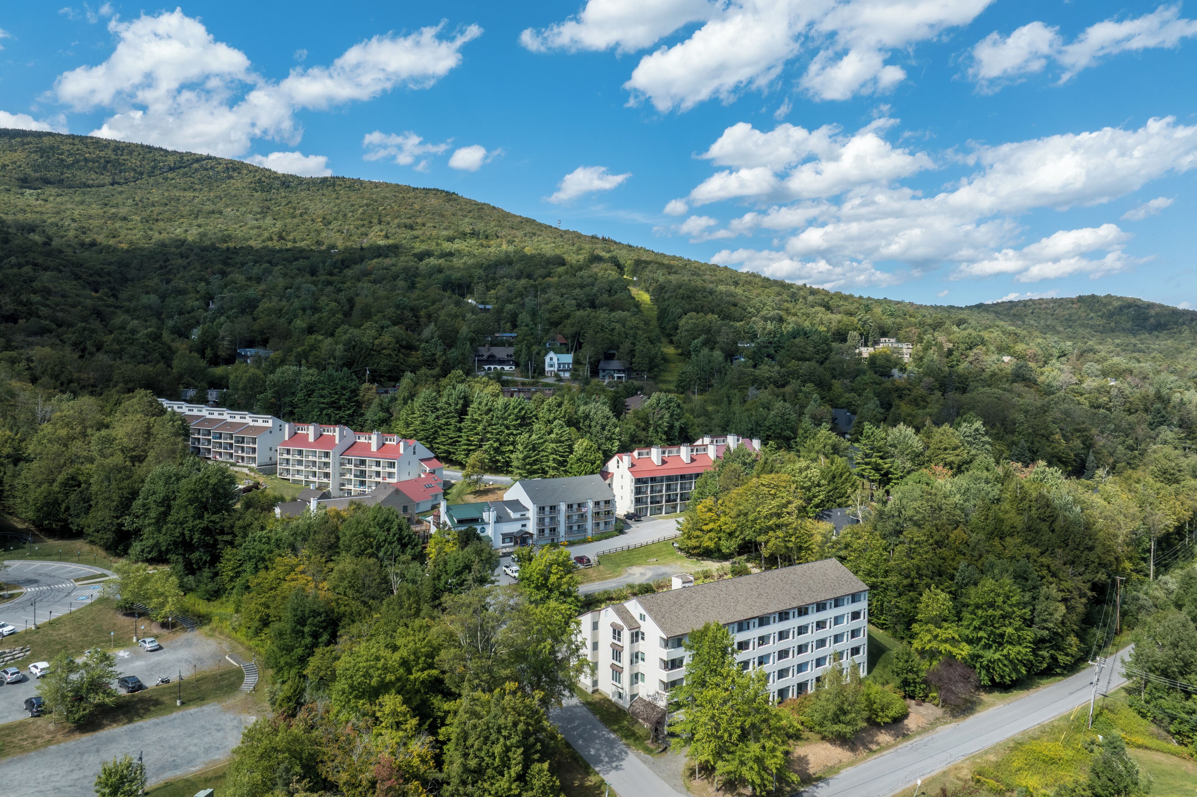 Un hotel de varios pisos con un patio central, rodeado de un bosque denso y colinas.