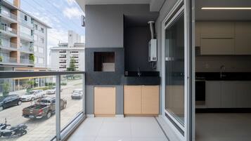 Un apartamento moderno con balcón, cocina con encimeras oscuras y vista a la calle.