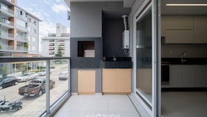 A modern apartment with a balcony, a kitchen with a black countertop, and a view of the street.